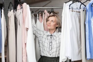 Woman choosing blouses at store clipart