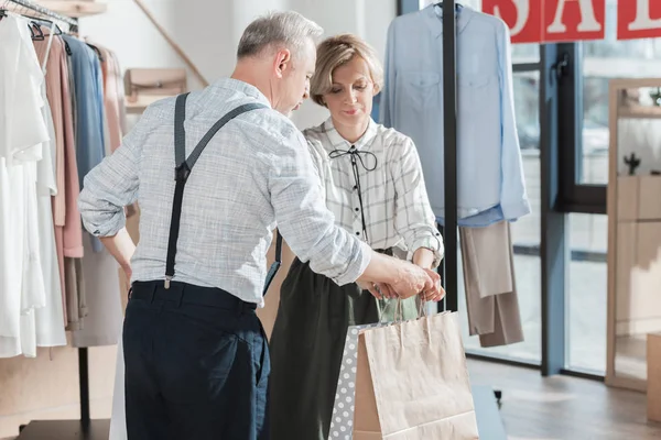 Mulher dando sacos de compras para o homem — Fotografia de Stock