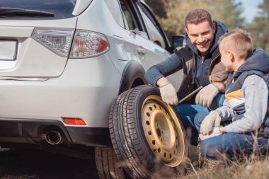 Father and son changing car wheel clipart