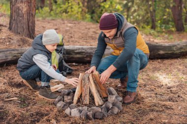 Father and son kindling bonfire  clipart