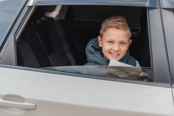 Мальчик с цифровым планшетом в машине — стоковое фото