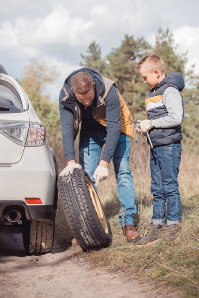 Father and son changing car wheel