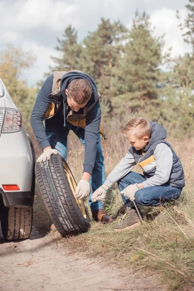 Padre e figlio che cambiano ruota dell'auto — Foto stock gratuita