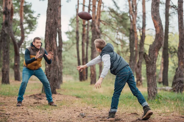 Vader en zoon spelen met de bal in het bos — Stockfoto