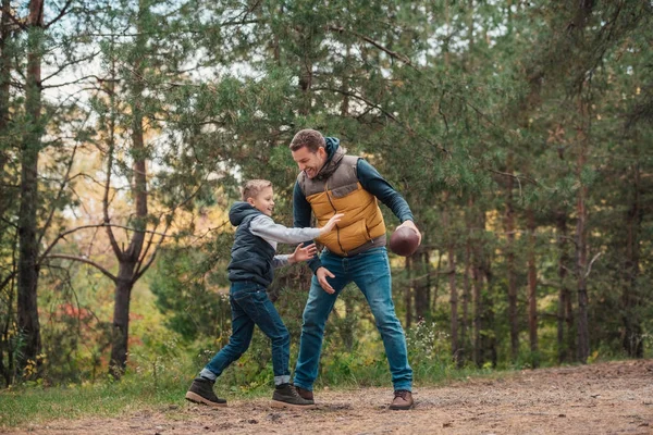 Батько і син грають з м'ячем у лісі — стокове фото