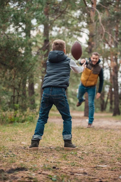 Vader en zoon spelen met de bal in het bos — Stockfoto