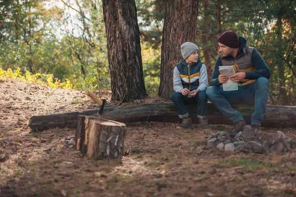 Far och son med karta i skogen — Stockfoto