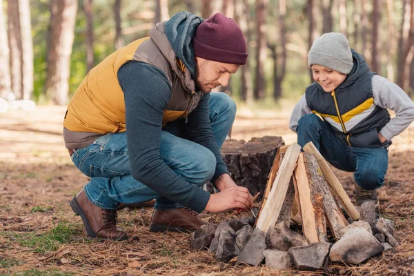 Father and son kindling bonfire — Stock Photo, Image