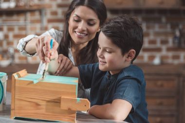 Mother and son painting birdhouse clipart