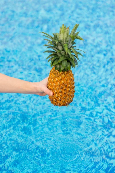 Woman holding pineapple over water — Stock Photo, Image