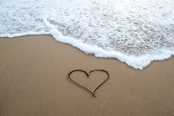 знак в форме сердца на песке
