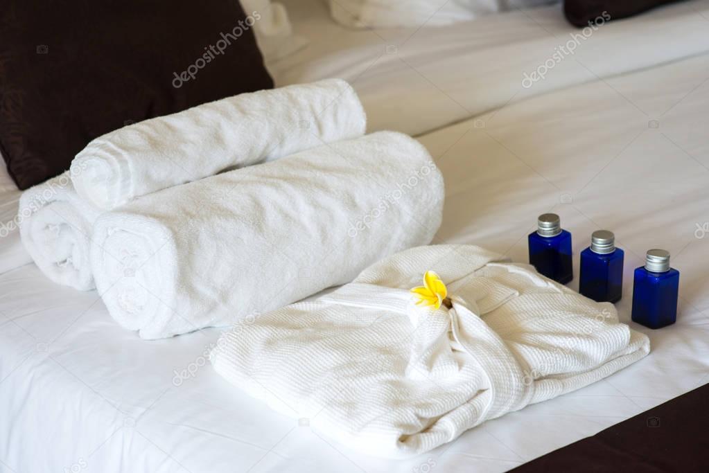 rolled towels and bathrobe on bed