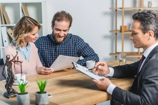 Smiling couple reading contract — Stock Photo, Image