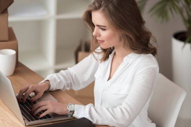 side view of businesswoman working on laptop at table clipart