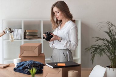 evde fotoğraf makinesi üzerinde office ürünleri fotoğraflara bakarken girişimci yan görünüm