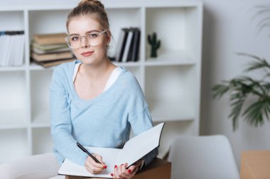 online mağaza sahibi kalem ve defter kameraya evde ofis seyir ile portresi