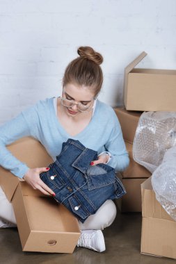 genç girişimci ambalaj ürünleri, ofis ev iken denim ceket karton kutu koyarak