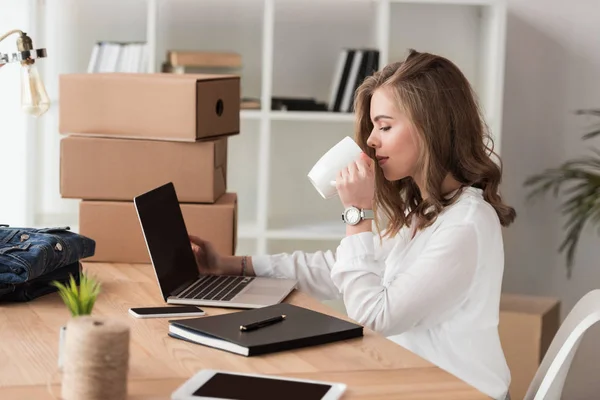 Widok Boku Bizneswoman Picie Kawy Podczas Pracy Laptopie Przy Stole — Zdjęcie stockowe