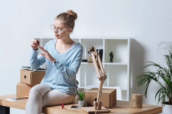 Retrato Mujer Joven Aplicando Esmalte Uñas Mientras Está Sentada Mesa —  Fotos de Stock