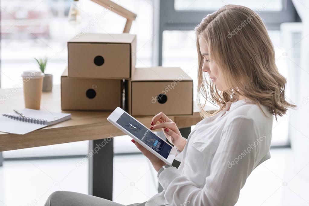 Side view of young businesswoman using digital tablet with tumblr app