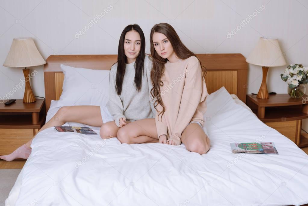 beautiful multiethnic women sitting on bed in bedroom