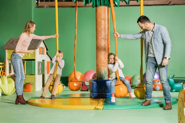 Smiling Parents Looking Cute Happy Children Swinging Swings Game Center — Stock Photo, Image