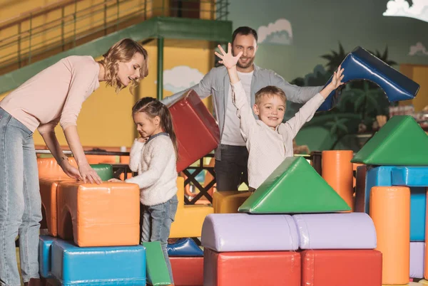 Família Feliz Com Duas Crianças Construindo Castelo Com Blocos Coloridos — Fotografia de Stock