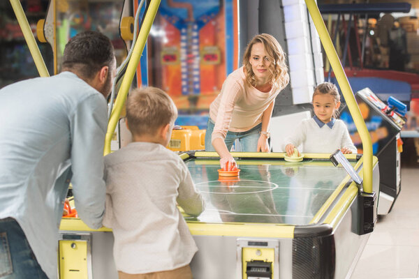 happy family playing air hockey together in entertainment center  
