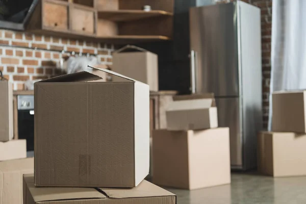 selective focus of cardboard boxes in empty kitchen during relocation