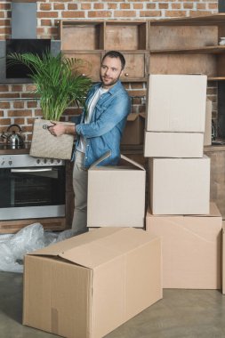 Holding adam gülümsüyor tesisi yeni evin içinde hareket ederken saksı 