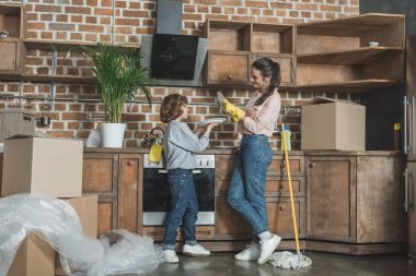 Anne ve oğul birbirlerini yeni dairede yer değiştirme sonra plakaları yıkarken gülümseyen