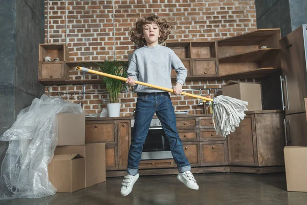 新しい家でモップでジャンプ幸せの小さな男の子 — ストック写真