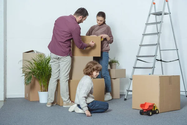 父母包装盒和儿子在地板上玩的搬迁 — 图库照片