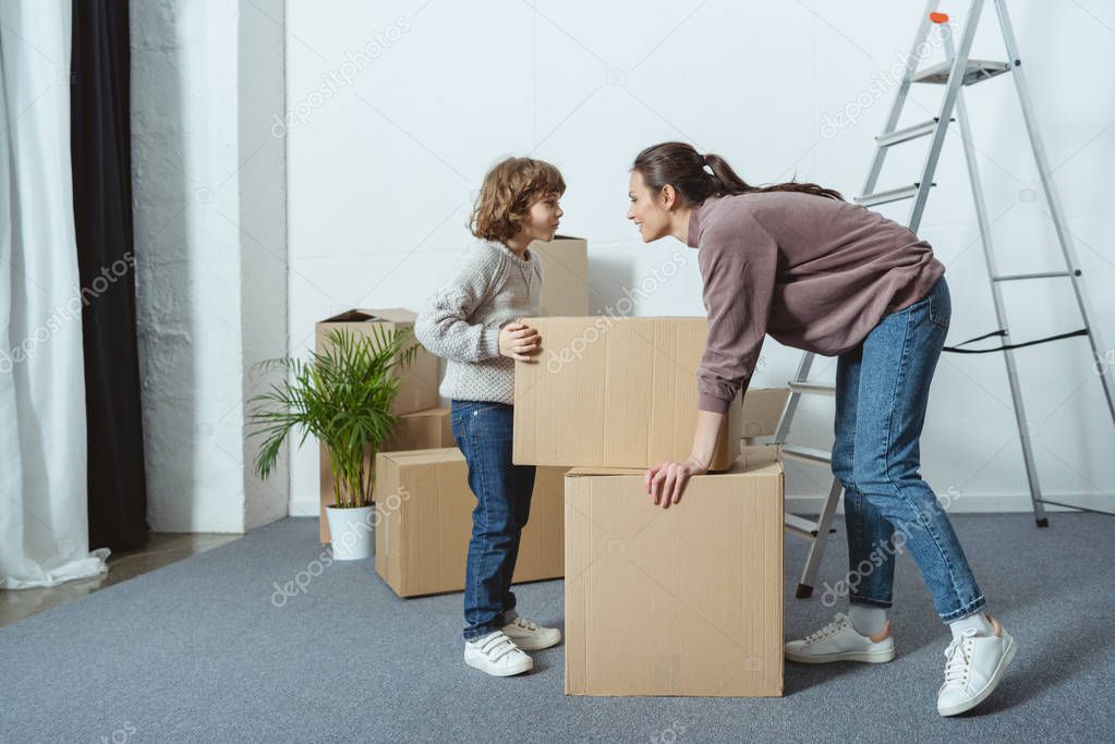 happy mother and son looking at each other while packing boxes during relocation