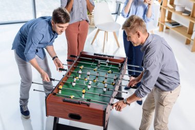 Modern ofis masa futbolu oynayan iş adamları