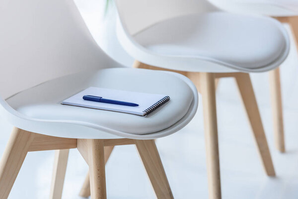Notepad and pen on chair in modern office