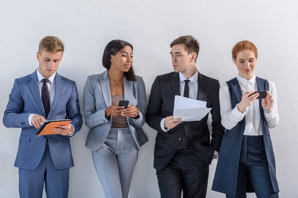 Group of diverse business people in suits standing by the wall