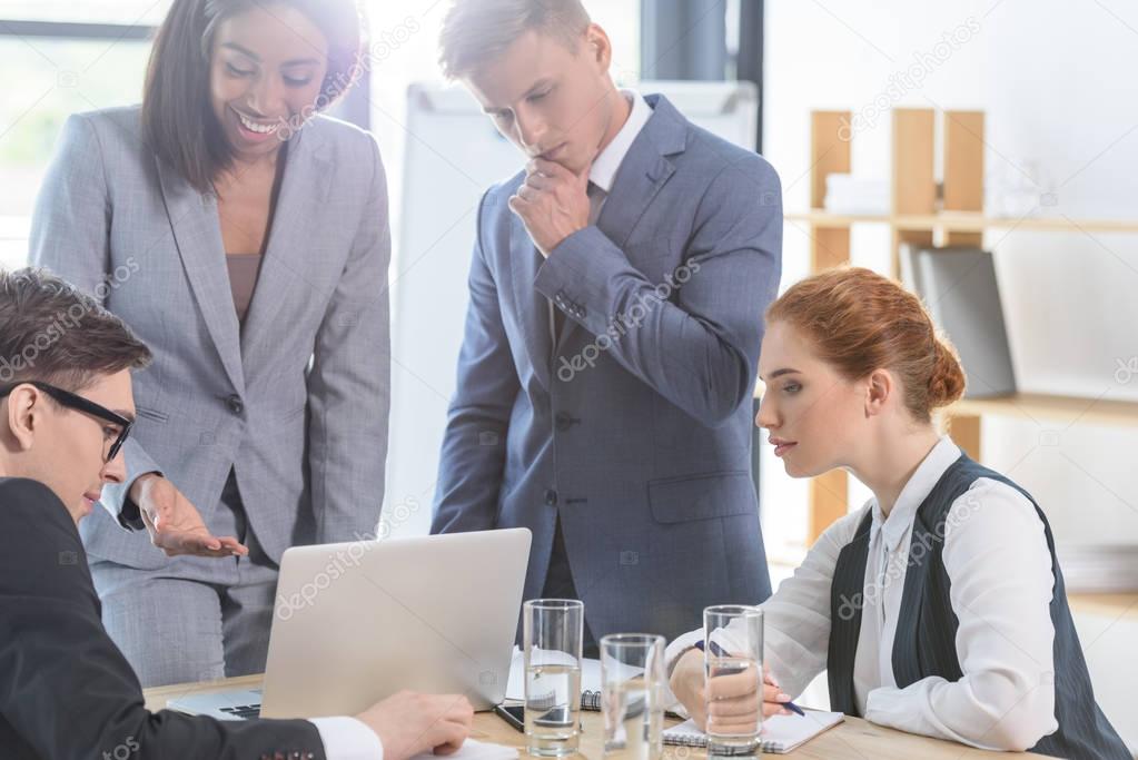 Successful team discussing project by laptop in modern office  