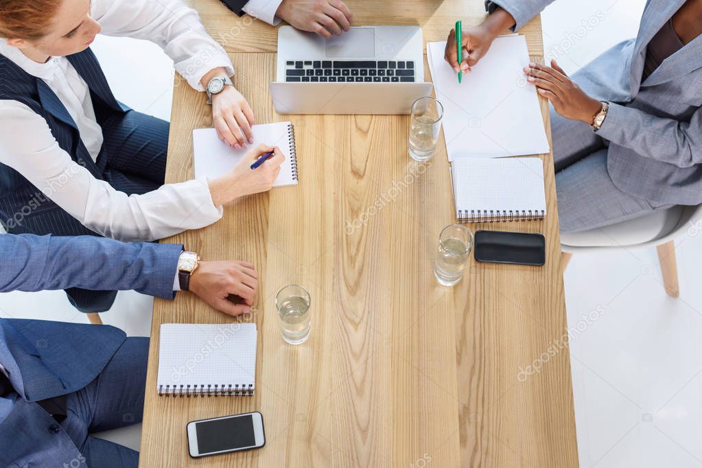 Business team writing in notepads during meeting in office
