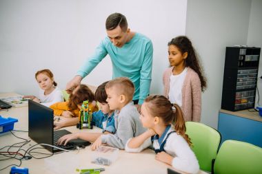 group of kids listening to teacher at machinery class clipart
