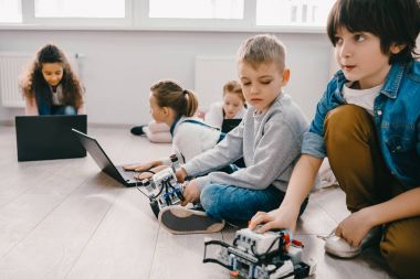 odaklı çocuklar dizüstü bilgisayarlar ile robotlar yerde otururken programlama kök eğitim kavramı
