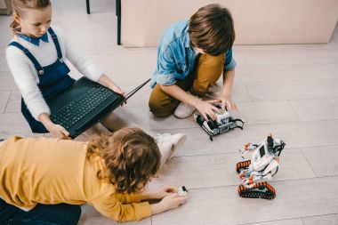 robotlar ve dizüstü bilgisayar ile kök Eğitim sınıf katında oturan çocuk yüksek açılı görünüş