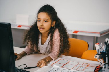 Afro-Amerikan kız öğrenci makineleri sınıfında bilgisayarla çalışma konsantre