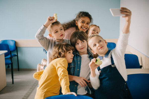 group of kids taking selfie at school classroom