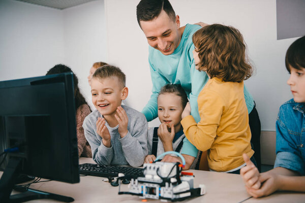 teacher helping his teen students with diy robot on stem education class