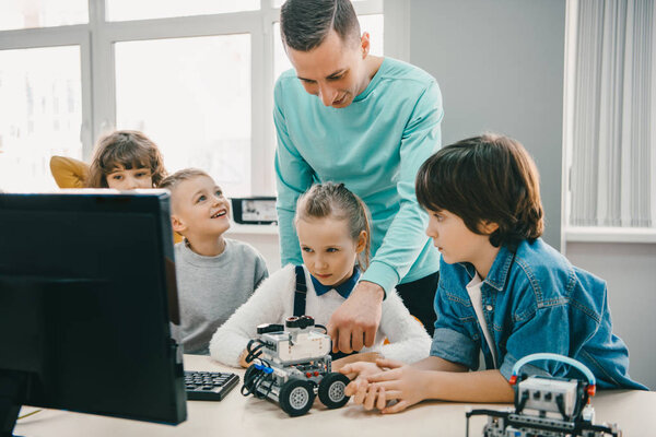teacher working with teen students on diy robot on stem education class