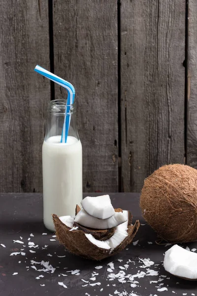 Coconut pieces with flakes and milk in bottle — Stock Photo