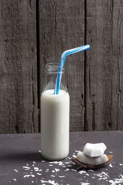 Kokosnussstücke mit Flocken und Milch in der Flasche — Stockfoto