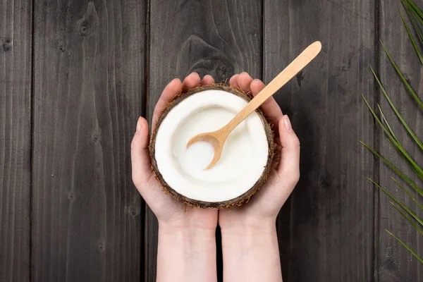 Manos sosteniendo coco con leche y cuchara - foto de stock