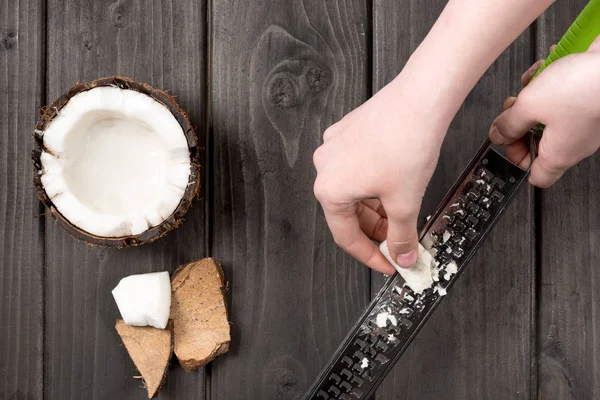 Hands slashing coconut pieces with grater — Stock Photo